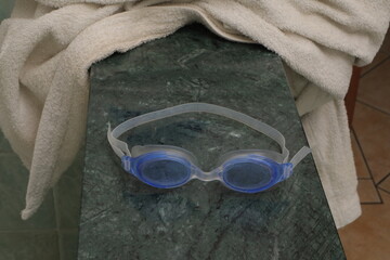 Swimming goggles on marble surface with towel