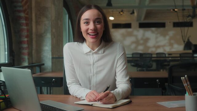 Thinking Caucasian businesswoman female girl business woman manager worker in office holding pen with notebook at table think student joyful create come up with idea insight writing notes smiling