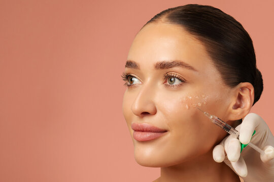 Cosmetologist making rejuvenating anti wrinkle injections on young woman face. Female aesthetic cosmetology in a beauty salon. Free space