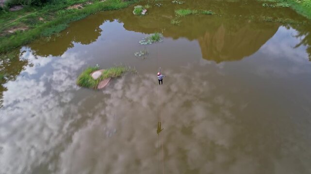 Tracking drone view of an adventurous girl zip-lining amidst the lush green hills of Ramanagara