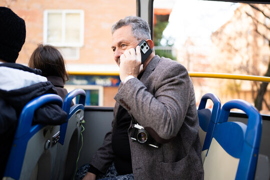 Man talking on smartphone aboard public bus during commute