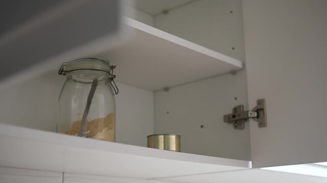 Woman opening almost empty pantry, food shortage and inflation concept