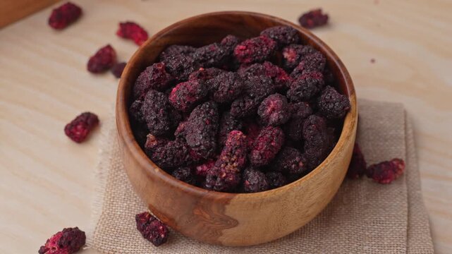 Dried black mulberries on a bowl closeup.
