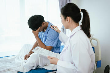 Fototapeta premium Female doctor comforting a distressed male patient sitting on a hospital bed, reviewing medical notes and offering support during a healthcare consultation.