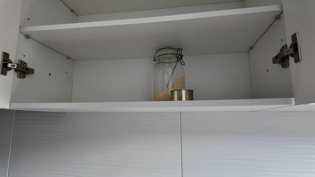 Woman opening almost empty pantry, food shortage and inflation concept