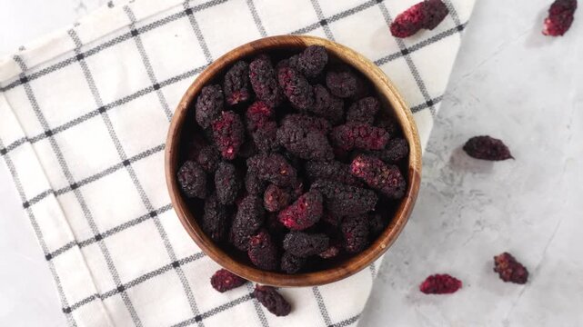 Dried black mulberries on a bowl closeup.
