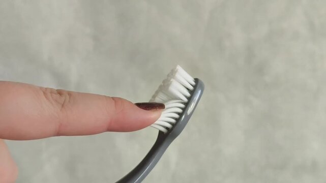 A woman's hand touches the bristles of a toothbrush, checking the level of hardness. Soft toothbrushes. Oral hygiene. Dentistry. Prevention of caries