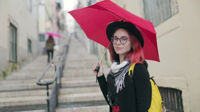 Young hipster woman with red umbrella standing on old city stairs
