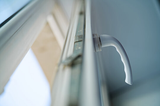 Low angle view of an open uPVC window sash with a handle and metal locking mechanism. Concept of glazing repair, installing fittings or house cleaning. Photo