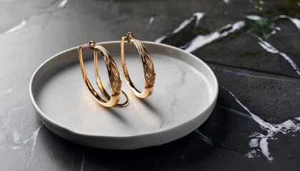 gold hoop earrings on plate marble background jewelry display