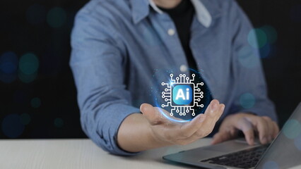 Business professional holding AI microchip icon above hand while using laptop, artificial intelligence technology, machine learning, digital transformation, data processing 