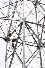 Fototapeta premium Pylon construction workers working on the top of power tower.