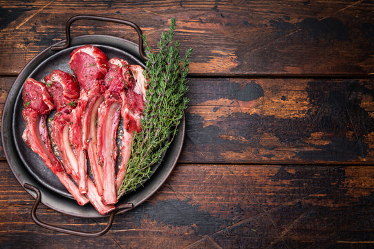 Raw lamb chop cutlets, fresh mutton meat for steaks with herbs. wooden background. top view
