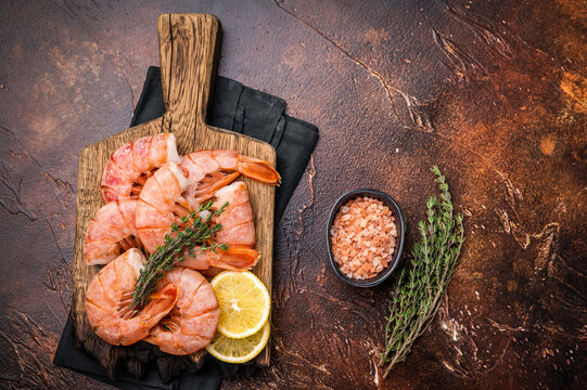 Fresh raw Headless Red Argentine shrimps, Prawns on wooden board. brown background. top view