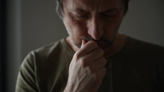 Thoughtful middle-aged man looking down in soft light portrait, 4K