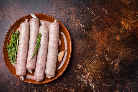 Raw Sausages with forcemeat mincemeat with herbs in plate. brown background. top view