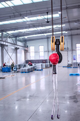 Close-up of a red safety helmet hanging from a crane hook in the Machinery & Iron Factory workshop
