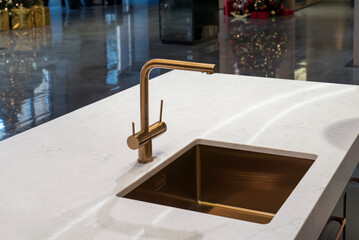 Gold kitchen faucet and undermount sink on white marble countertop