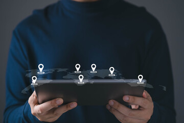 Global business expansion concept with world map and location pins on tablet screen, symbolizing...