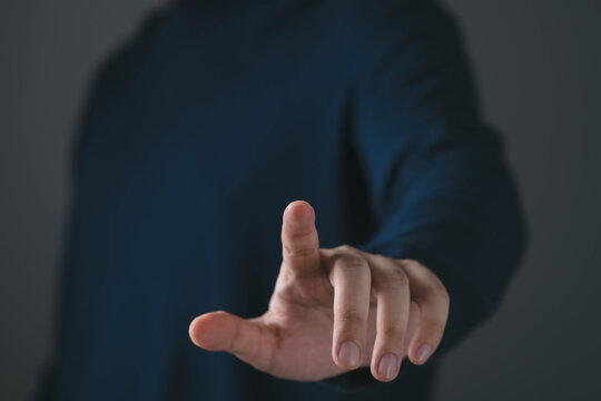 Close up of a hand pointing forward, index finger extended toward camera, symbolizing choice, selection, direction and decision making. Concept of leadership, focus, target and action.