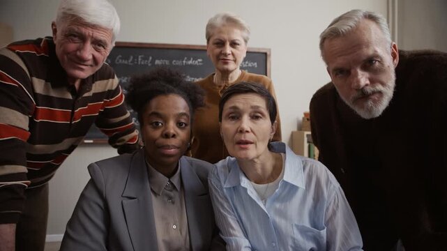POV of Black female teacher and Caucasian senior students looking directly at camera and sharing discussion on digital education during interactive classroom lesson
