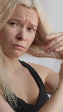 Female Inspects Hair For Signs Of Harm. Closeup Woman Examining Dry Hair Strands With Worried Expression, Fingertips Testing Texture And Breakage, Intimate Indoor Grooming Moment Showing Vulnerability