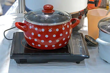Retro red polka dot design metal pot on small stove inside kitchen interior