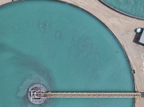 Aerial view of turquoise waters swirling within circular ponds, connected by a slender bridge, creating a striking geometric pattern against the arid landscape, Phoenix, Arizona, United States.