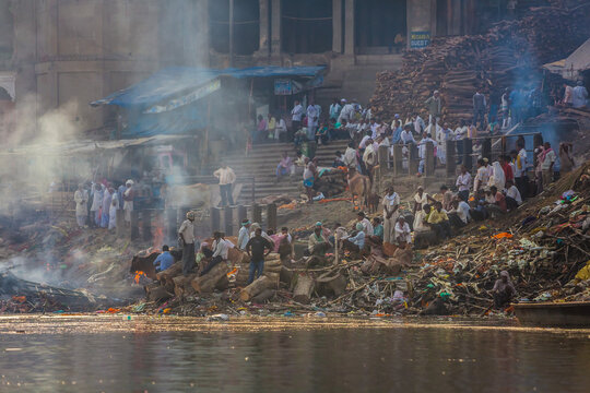 Varanasi, India - 19 March 2012: Aerial view of Manikarnika Ghat, where the sacred Ganges reflects the earthy tones of the cremation pyres and the vibrant attire of the crowd.