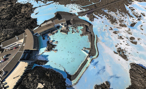 Aerial view of the striking contrast of the bright turquoise waters of the Blue Lagoon against the stark black lava fields, Landmannaleid, Rangarthing ytra, Iceland.