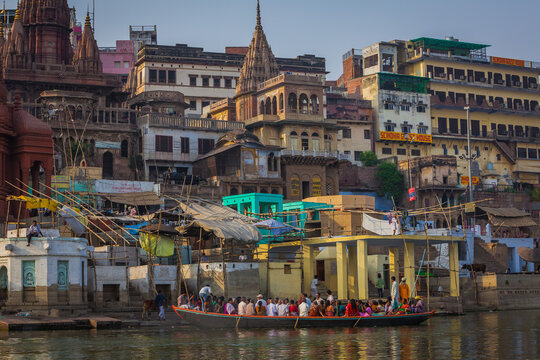 Varanasi, India - 19 March 2012: Aerial view of the ghats bustling with life, temples piercing the skyline, and boats gliding on the Ganges, reflecting the city's vibrant spirit.