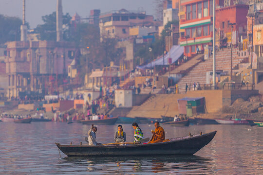 Varanasi, India - 20 March 2012: Aerial view of boats gliding along the Ganges, framed by the city's vibrant ghats and temples, bathed in the soft light of dawn.