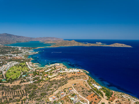 Aerial view of the Spinalonga peninsula, where the turquoise waters meet the rugged coastline, offering a picturesque contrast under the clear sky, Spinalonga, Lasithi, Greece.