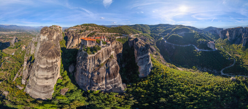 Aerial view of the majestic monasteries perched atop towering rock formations, casting long shadows across the lush valley, Kalabak, Trikala, Greece.