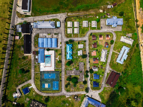 Aerial view of rooftops in a compound setting with swimming pool and tennis court, framed by lush greenery, Port Harcourt, Rivers, Nigeria.