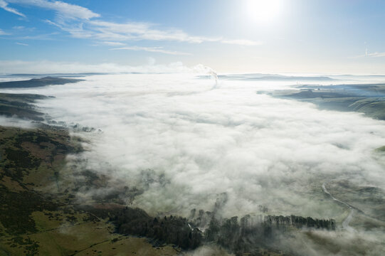 Aerial view of the Hope Valley shrouded in a sea of ethereal mist, the landscape transformed into a dreamlike panorama under the radiant sun, Hope Valley, England, United Kingdom.