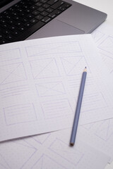 Hand-Drawn Website Wireframes Close-up on Dot-Grid Paper with Pencil and Laptop Keyboard