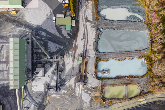 Aerial view of industrial landscape revealing the textures of earth and machinery, with a series of settling ponds reflecting the sky, Peumerit, Brittany, France.