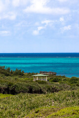 Fototapeta premium Tropical coastline with turquoise ocean and small pavilion under a blue sky 青空の下に広がるターコイズブルーの海と小さな東屋のある海岸風景