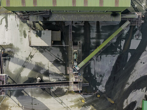 Aerial view of industrial architecture casting shadows on the ground, creating a monochromatic landscape punctuated by metallic structures, Peumerit, Brittany, France.