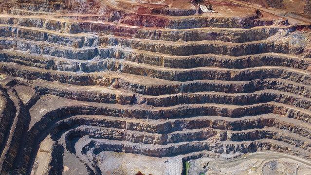 Aerial view of layered earth tones cascade down the open-pit mine's terraced landscape, exposing the raw beauty of the mineral-rich terrain, Rio Tinto, Andalusia, Spain.