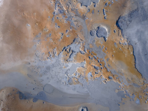 Aerial view of a surreal landscape where rust-colored earth meets cool, ethereal pools, creating an otherworldly tableau of textures and tones, Hafnarfjaroarkaupstaour, Iceland.