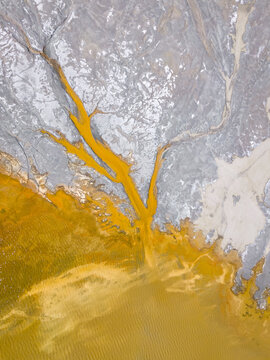 Aerial view of ochre waters flow, staining the landscape with veins of vibrant color against the stark, pale earth, creating a surreal, textured panorama, RIO TINTO, Andalusia, Spain.