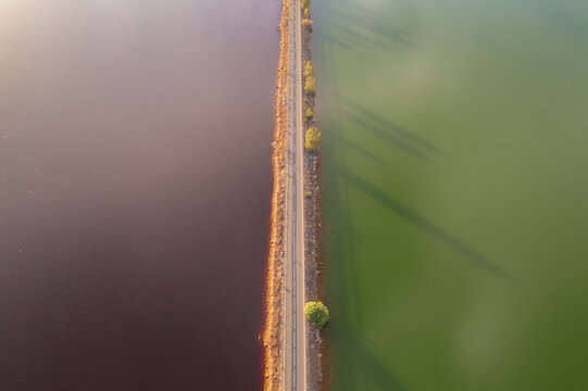 Aerial view of a striking contrast of colors between deep red and vibrant green waters separated by a narrow road, Minas de Riotinto, Andalusia, Spain.