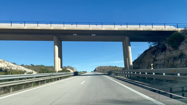 Carretera y conducci&oacute;n de coche desde dentro con velocidad en viaje y visi&oacute;n conductor pasando por puente