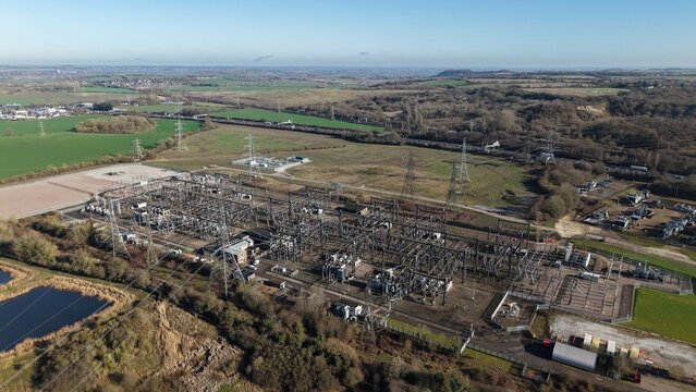 Aerial view of the sprawling National Grid Sundon Substation, a metallic labyrinth amidst the verdant fields of Luton, under the expansive sky, Luton, United Kingdom.