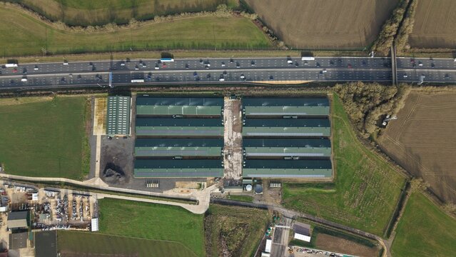 Aerial view of a sprawling industrial complex mirroring the adjacent highway's ceaseless flow, Horse Close Green Power, Northampton, United Kingdom.