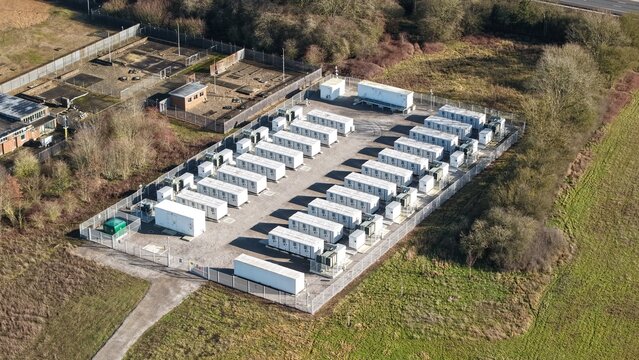 Aerial view of the Battery Energy Storage System at National Grid Sundon Substation, a symphony of white containers amidst the green and brown landscape, Luton, United Kingdom.