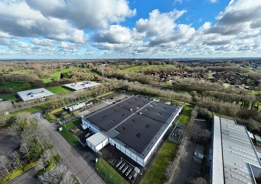Aerial view of the nLighten Data Centre with its stark architecture contrasting against the lush greenery and cloud-dappled sky, Milton Keynes, United Kingdom.