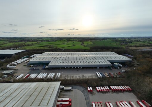 Northampton, United Kingdom - 14 February 2026: Aerial view of the Carlsberg distribution centre, where rows of trailers form a striking pattern against the vast, verdant landscape.